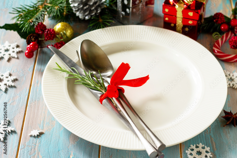 Christmas table setting. Festive plate and cutlery with decor on festive table.
