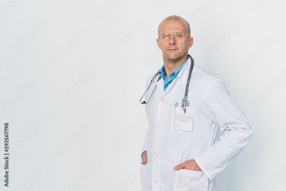 Young serious clinician in whitecoat keeping his hands in pockets Young serious clinician in whitecoat keeping his hands in pockets