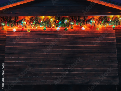 Christmas fir tree garland with christmas tree decoration on wooden house wall. Bright Christmas and New Year background with empty space for text