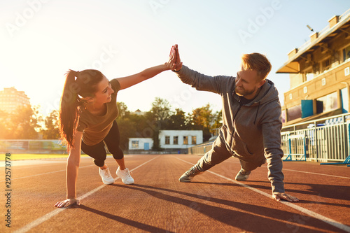 Young couple doing pushups in the stadium photo