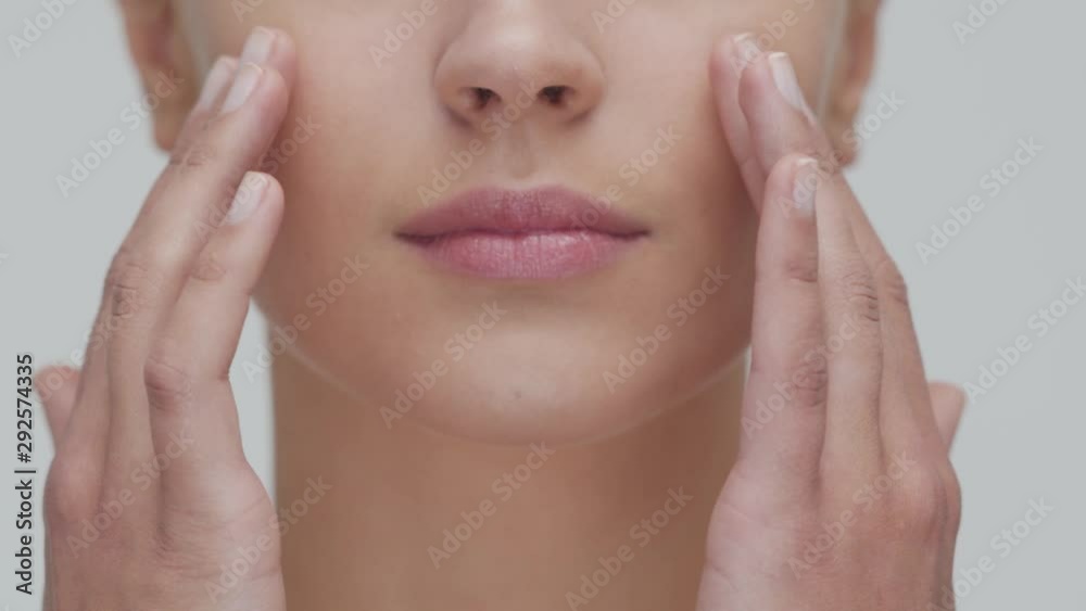 Studio portrait of young, beautiful and natural blond woman applying skin care cream. Face lifting, cosmetics and make-up.