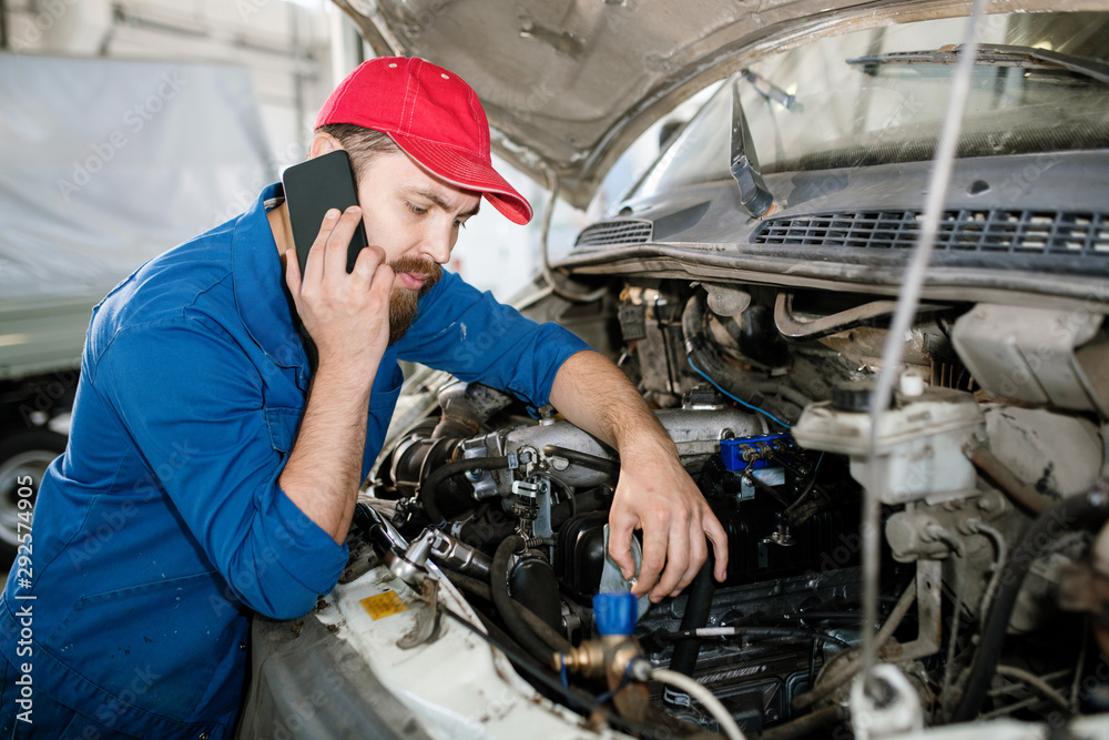 Master of technical service using smartphone while consulting one of clients