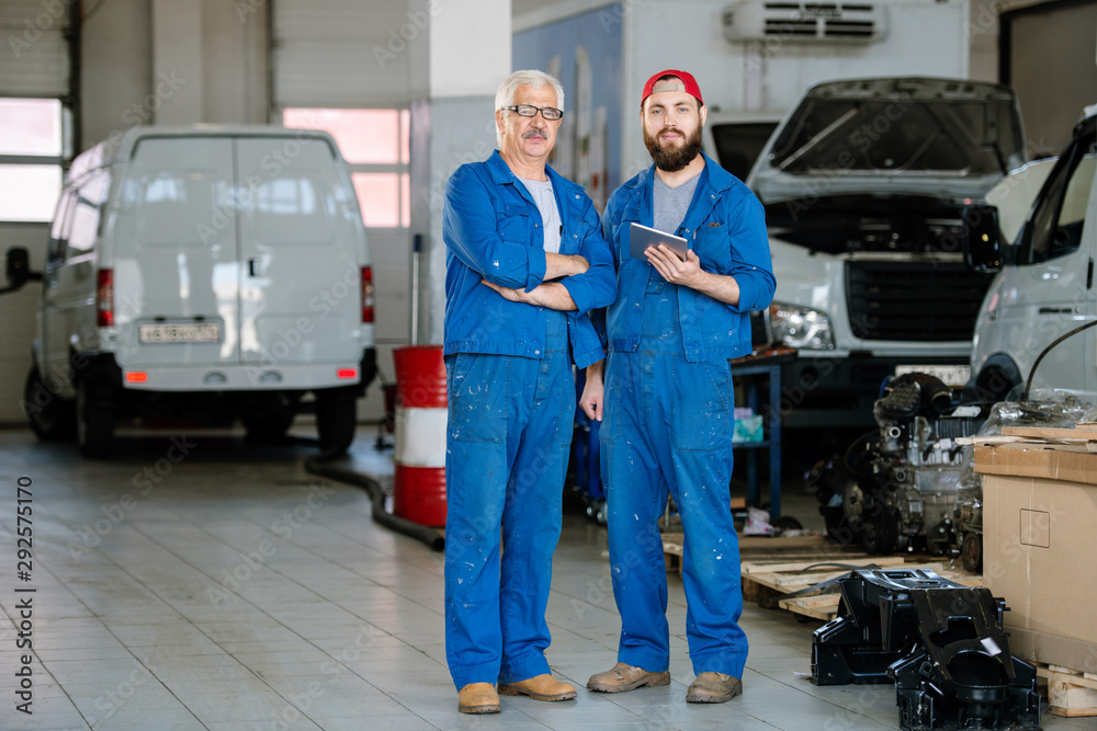 Two professional technicians of machine repair service in blue workwear