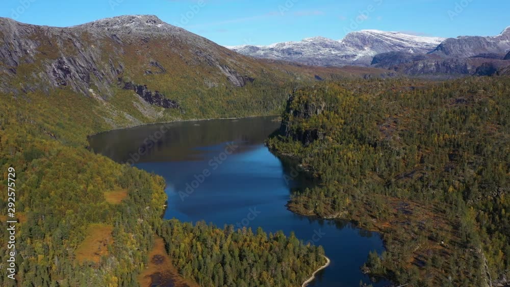 Orbital aerial drone shot over a beautiful wild landscape with snow-capped mountains, huge blue lake and forest o a sunny day. Orbital aerial drone shot over a beautiful wild landscape with snow-capped mountains, huge blue lake and forest o a sunny day.