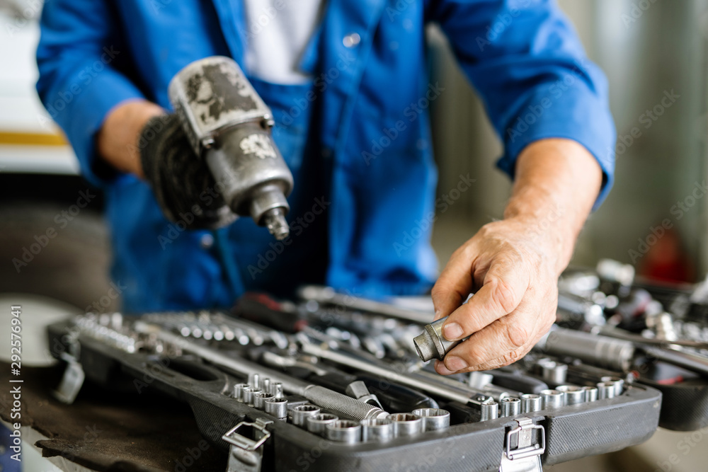Mature technician or repairman taking one of iron nozzles for technical drill Mature technician or repairman taking one of iron nozzles for technical drill