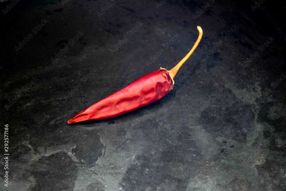 One pod bitter red pepper on a black metal tray, dried chili pepper. One pod bitter red pepper on a black metal tray, dried chili pepper.