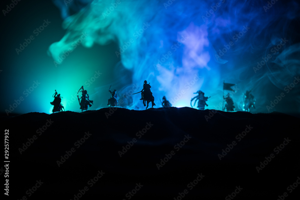 Medieval battle scene with cavalry and infantry. Silhouettes of figures as separate objects, fight between warriors on dark toned foggy background. Night scene. Medieval battle scene with cavalry and infantry. Silhouettes of figures as separate objects, fight between warriors on dark toned foggy background. Night scene.