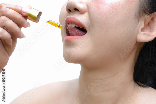 Close up young Asia woman holding a dropper sublingual cannabis oil Dosing