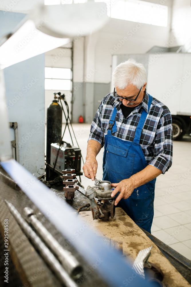 Senior professional technician in overalls and shirt working with wrench Senior professional technician in overalls and shirt working with wrench