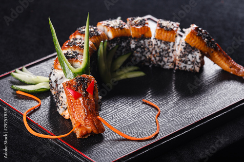 Sushi dragon with eel, cucumber and avocado on a black background. Japanese food, tasty of meal for lunch