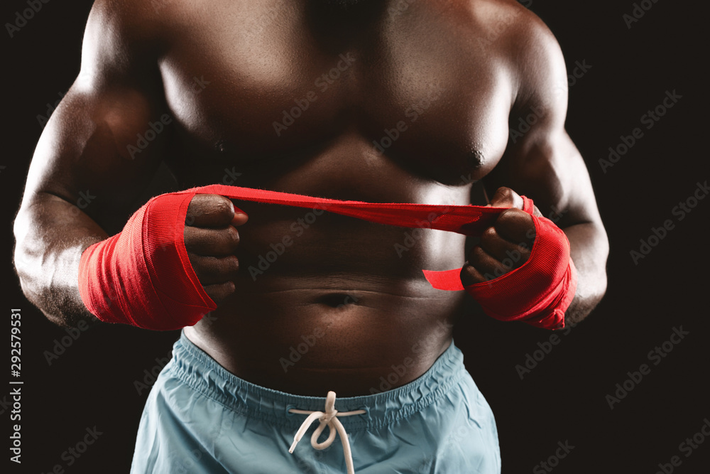 Naklejka premium Professional boxer pulling red sports bandage over black background