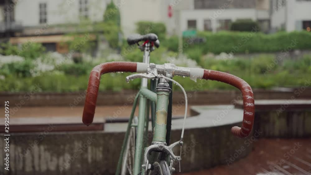 Wet handlebars with brown handles and bike seat on a rainy day. Close up Wet handlebars with brown handles and bike seat on a rainy day. Close up
