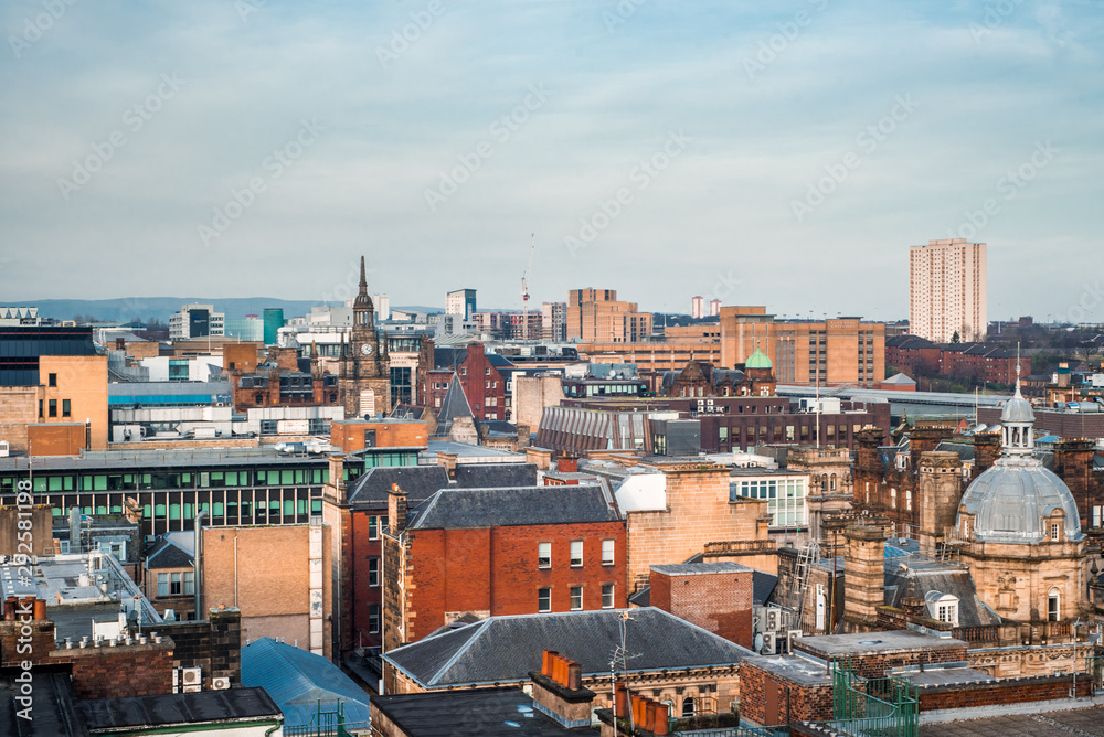 A wide rooftop view looking out over the buildings and architecture of Glasgow city centre in evening light, Scotland