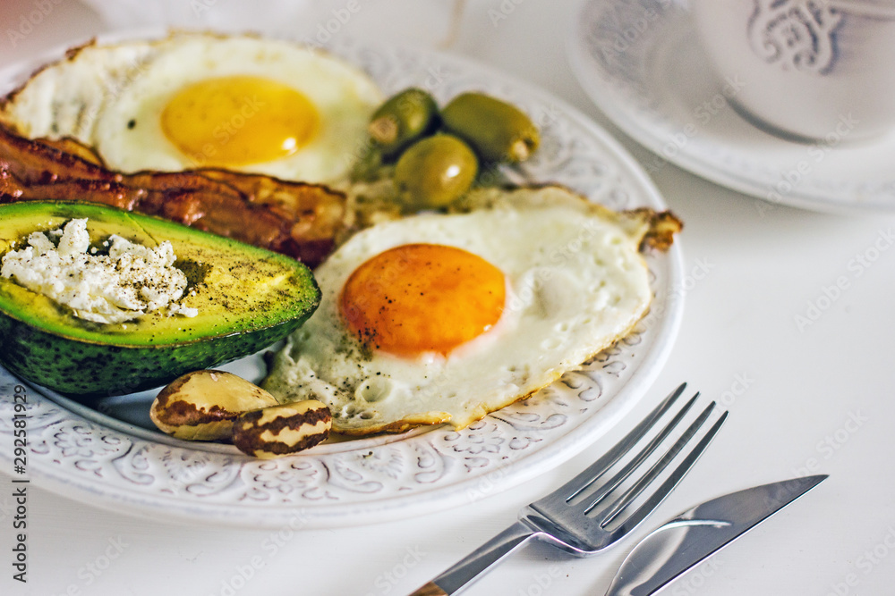 Keto Diet LCHF Keto breakfast. Fried eggs with bacon, avocado, cream cheese, nuts, olives and coffee on a white plate on a light background. Low carb diet concept. high fat diet. Keto bacon and eggs Keto Diet LCHF Keto breakfast. Fried eggs with bacon, avocado, cream cheese, nuts, olives and coffee on a white plate on a light background. Low carb diet concept. high fat diet. Keto bacon and eggs