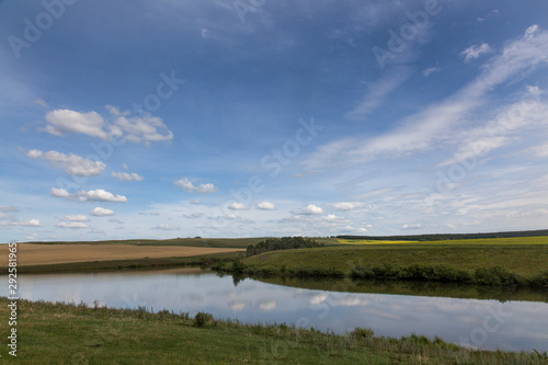 Reflection of yellow fields and cloudy sky in the lake.