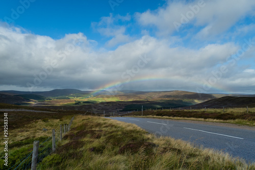Arcoíris entre montañas en la carretera, Escocia