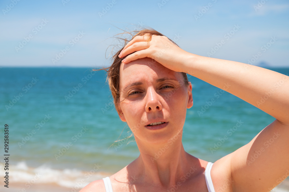 Woman with headache on sunny beach. Young woman having sunstroke. Health problem on vacation. Medicine on vacation Woman with headache on sunny beach. Young woman having sunstroke. Health problem on vacation. Medicine on vacation