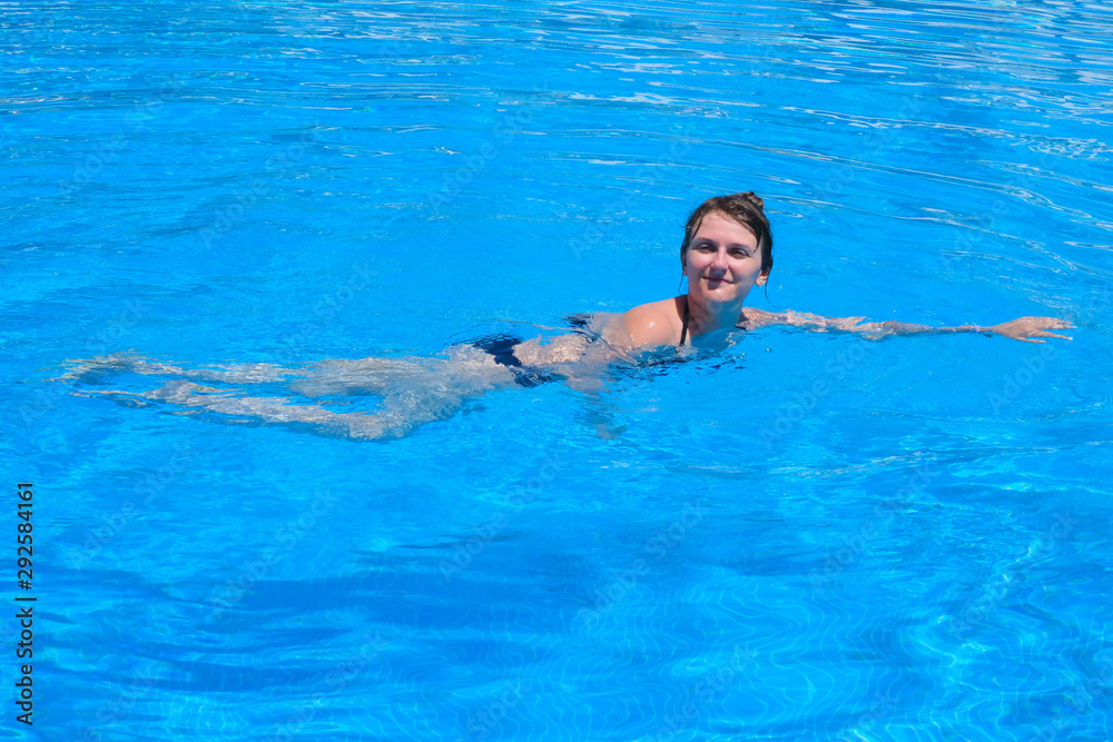 Girl swimming in pool, close up on blue water