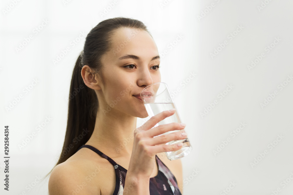 Millennial woman drinking clean fresh water after training Millennial woman drinking clean fresh water after training