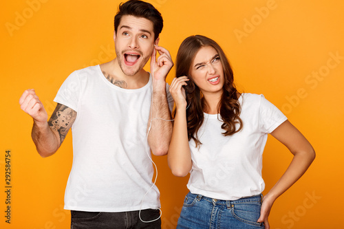Foto Different musical tastes. Man enjoying music, woman doesn't like
