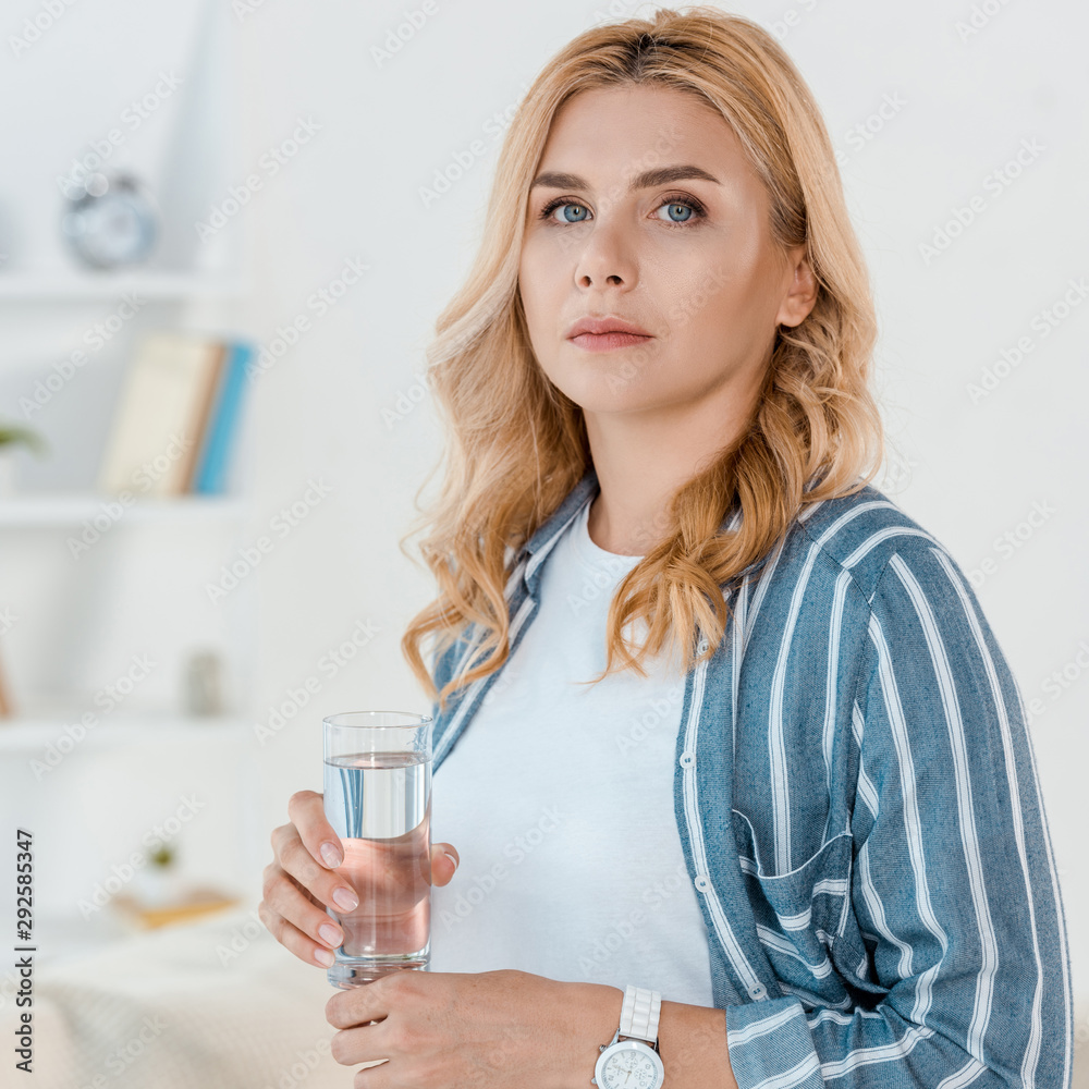 sad woman looking at camera while holding glass with water sad woman looking at camera while holding glass with water