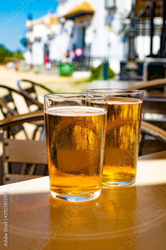 Cold amber color light spanish beer served in glass in outdoor cafe in town on sand, El Rocio in Andalusia, Spain