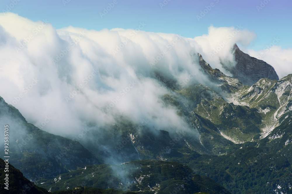 Dense clouds rolling over mountain range. Weather is changing in Julian Alps in Slovenia