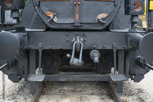 Industrial or vintage technology background featuring detail of old steam locomotive front view with head lights, metal rivets and hook railway coupling