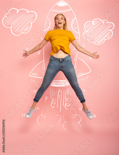 Girl jumps on pink background ready to fly like a rocket. Concept of freedom, energy and vitality photo