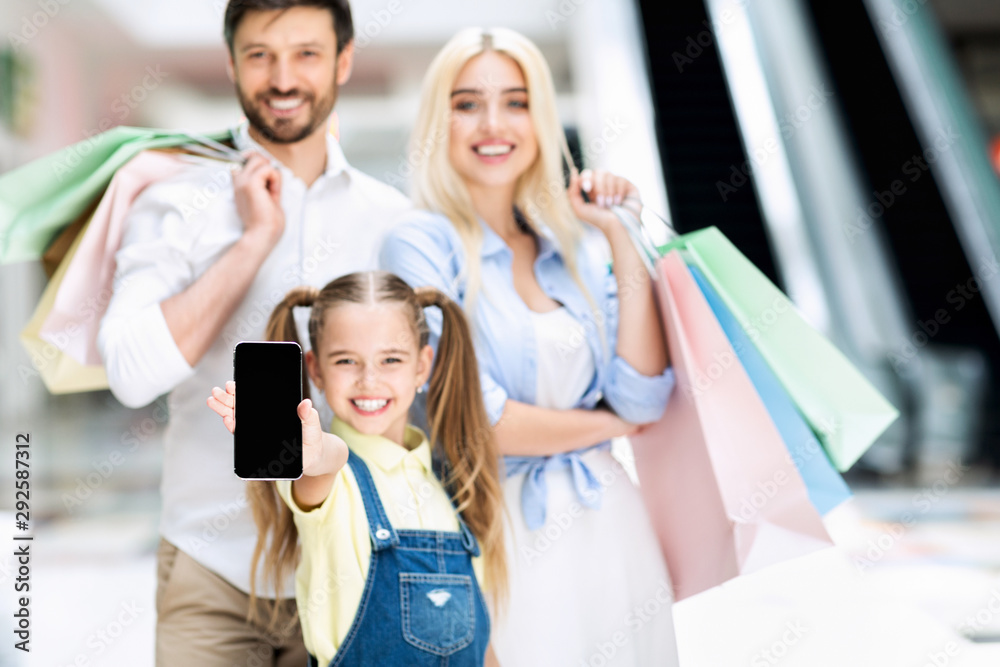 Obraz premium Happy Family Showing Phone Screen Standing In Shopping Mall, Mockup