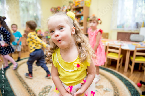 Positive girl with down syndrom looking at camera, party in rehabilitation center