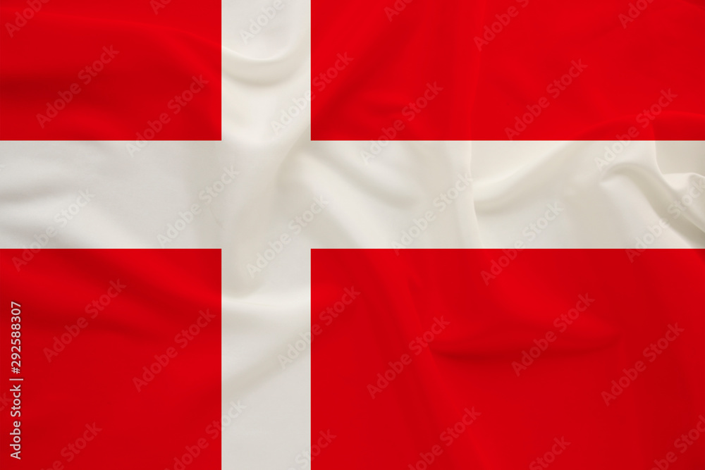Obraz premium The national flag of the country of Denmark on the gentle silk with folds from the wind, the concept of travel, immigration, politics, copy space, close-up
