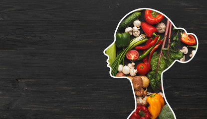 Woman with fresh vegetables in her body on wood