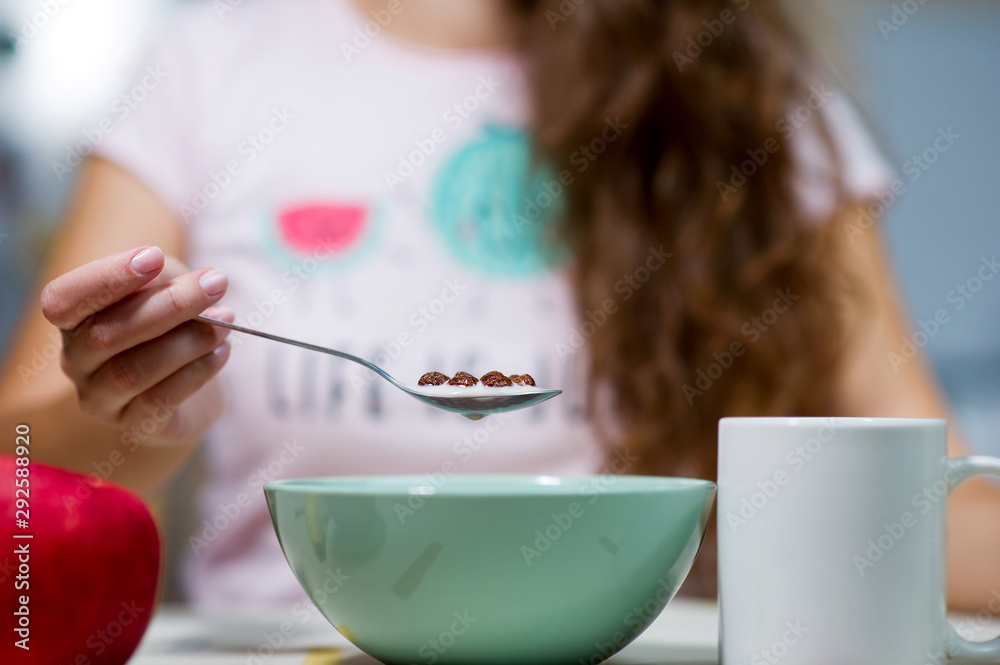 young woman with long hair holding a spoon with chocolate cereal over a plate young woman with long hair holding a spoon with chocolate cereal over a plate