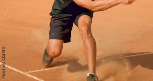 A Tennis player sprints across a clay tennis court to playa shot in slow motion. photo