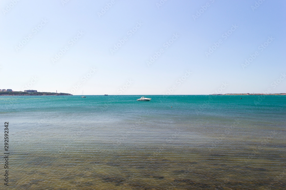 Scenic view on seascape from sea bay. Boats and ships in the distance. Skyline, coast and clear sky in frame. Vacation at the sea background.