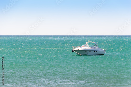 White boat anchored in a turquoise water of sea bay. Skyline and clear sky in frame. Vacation at sea. © Jekh