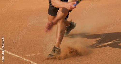 A Tennis player plays a great shot on a clay tennis court in slow motion.