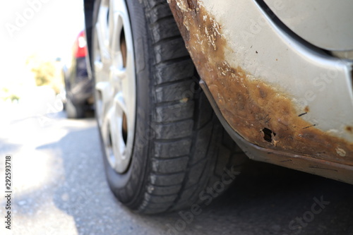 Grey car with rust on door sill and fender