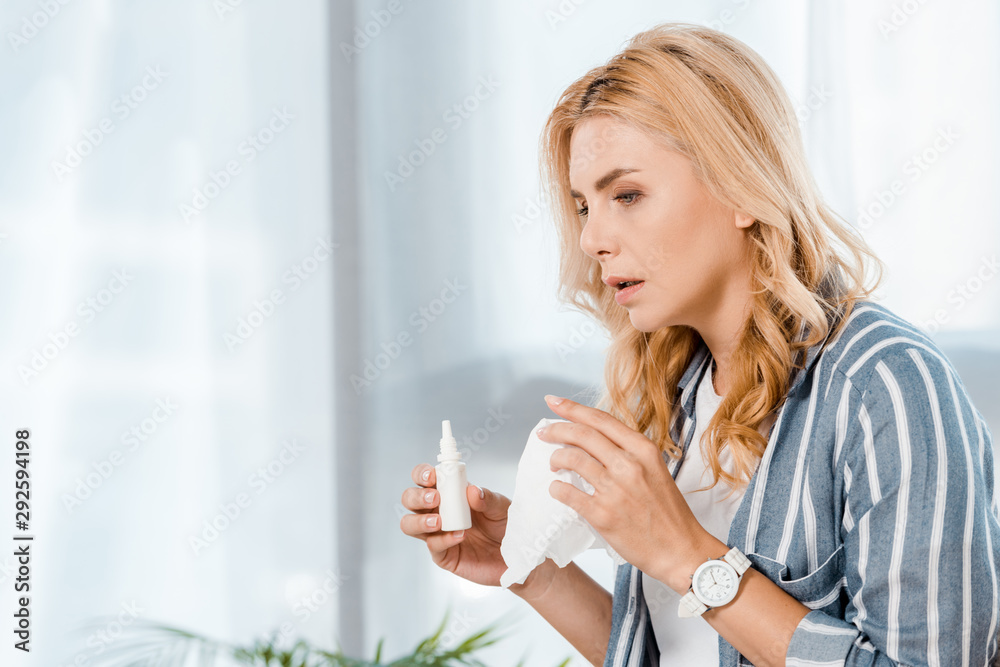 sick woman holding nasal spray and napkin at home sick woman holding nasal spray and napkin at home