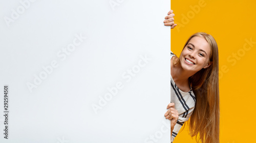 Beautiful teenage girl looking out of white blank placard
