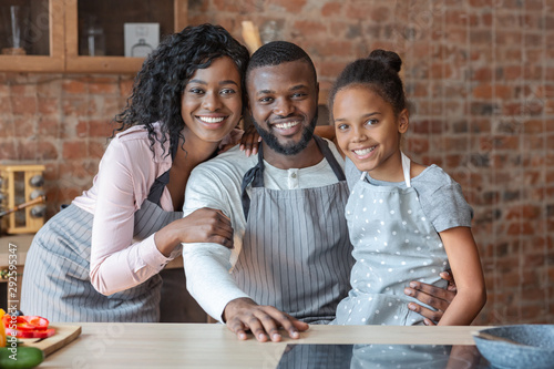 Happy family of three embracing at kitchen