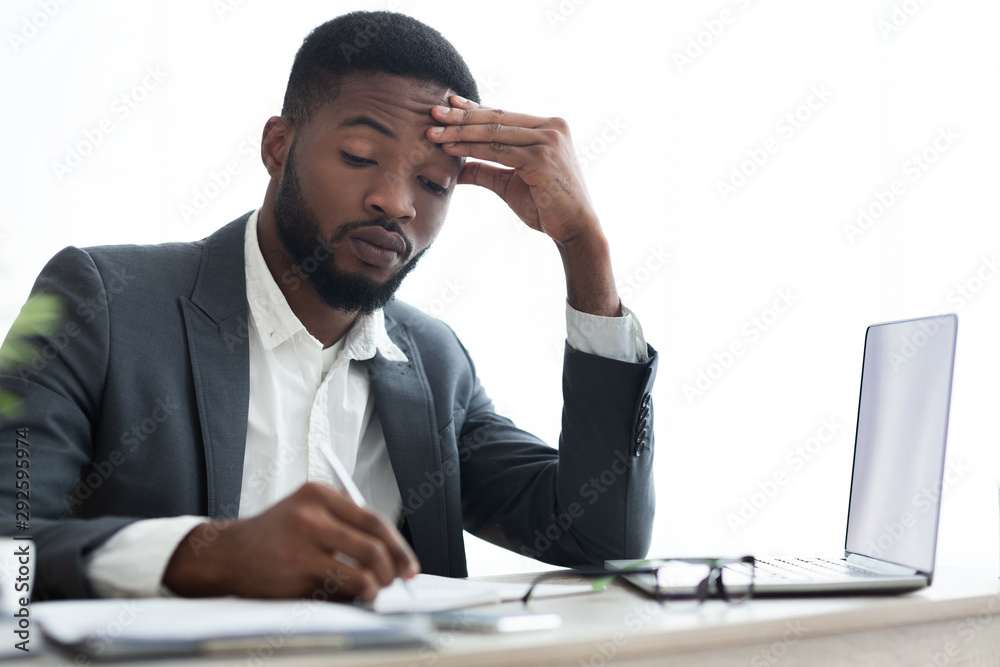 Focused employee taking notes in notebook at workplace in office Focused employee taking notes in notebook at workplace in office