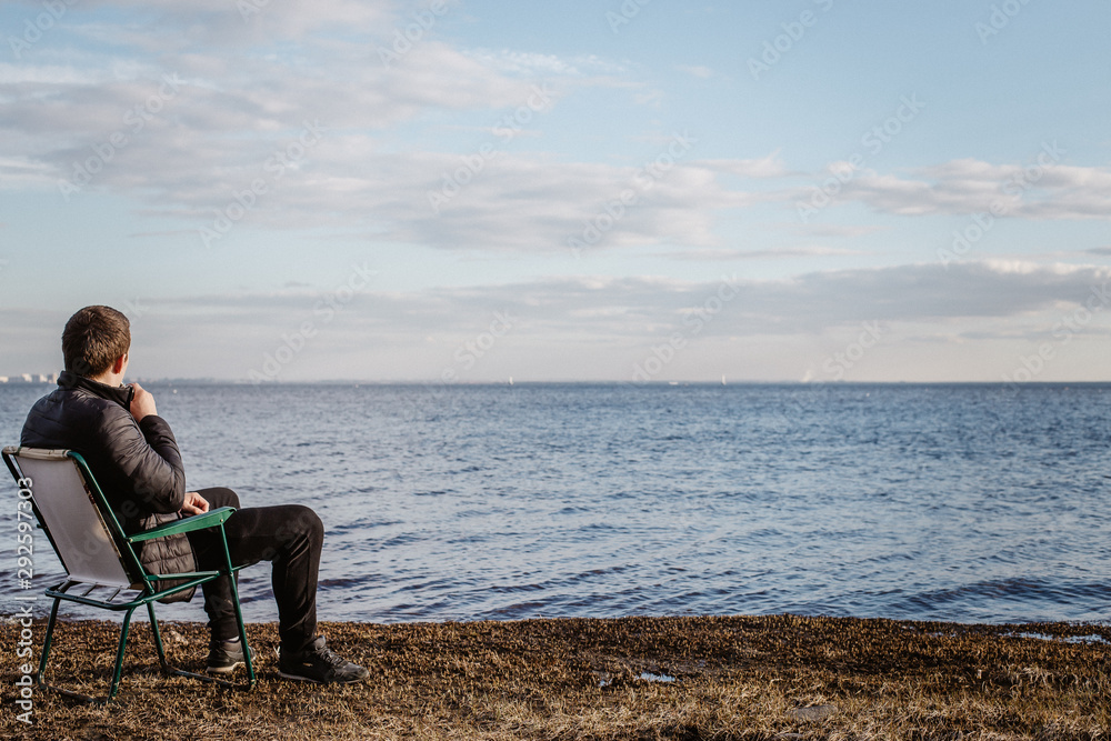  A man sits on a chair by the bay and looks at the horizon