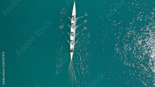 Aerial top down photo of sport canoe operated by team of young men in open ocean deep blue sea
