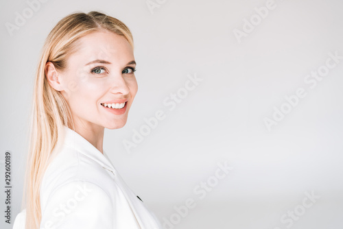 Fototapeta smiling beautiful young blonde woman isolated on grey