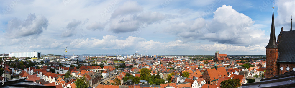 panorama cityscape of the old town of wismar, aerial high angle view from the shipyards at the baltic sea to the harbor over the roofs to the st. georgen church, sky with clouds, copy space