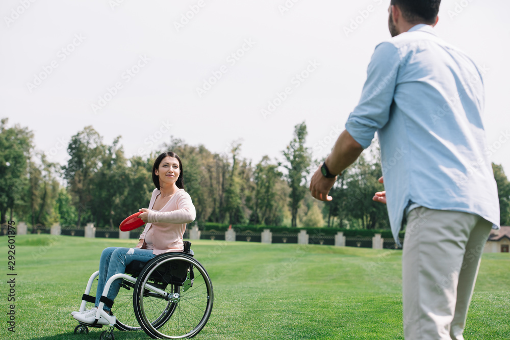 young disabled woman throwing flying disc to boyfriend in park young disabled woman throwing flying disc to boyfriend in park