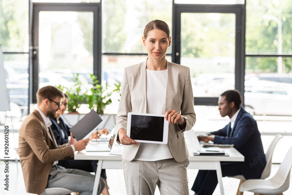 front view of smiling beautiful businesswoman holding digital tablet with blank screen in office front view of smiling beautiful businesswoman holding digital tablet with blank screen in office