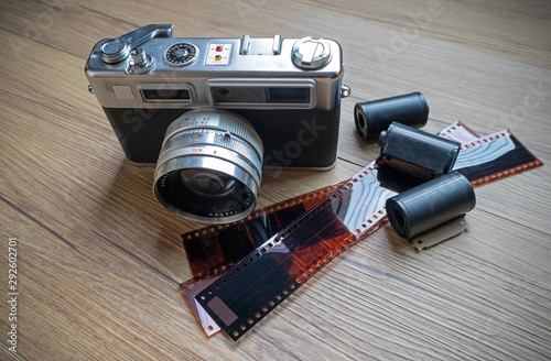Rangefinder film camera with 35mm film rolls on wooden table.